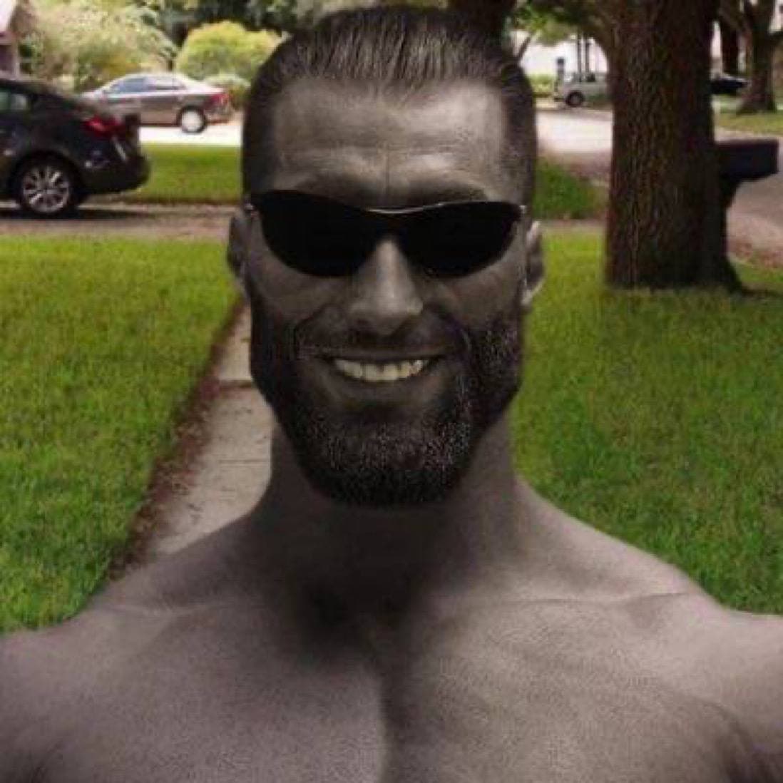 Muscular man in sunglasses smiling in a yard.