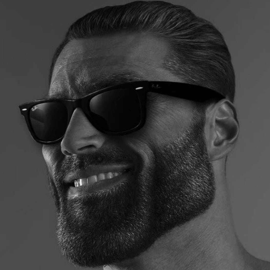 Muscular man with sunglasses and a beard smiling confidently.