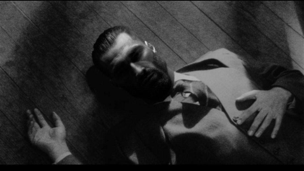 A confident man lying on the floor in a suit.