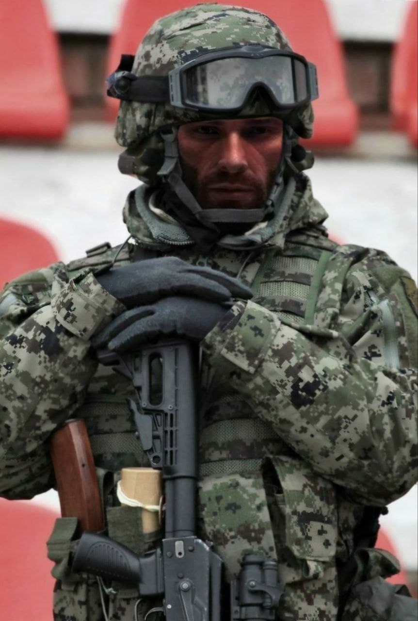 Soldier in tactical gear holding a rifle.