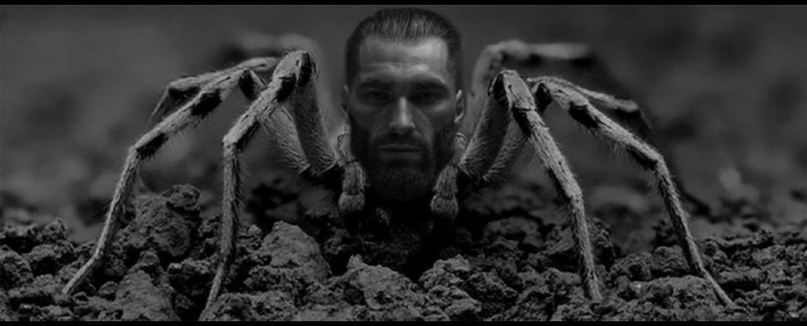 Man's face merged with a spider, emerging from the ground.