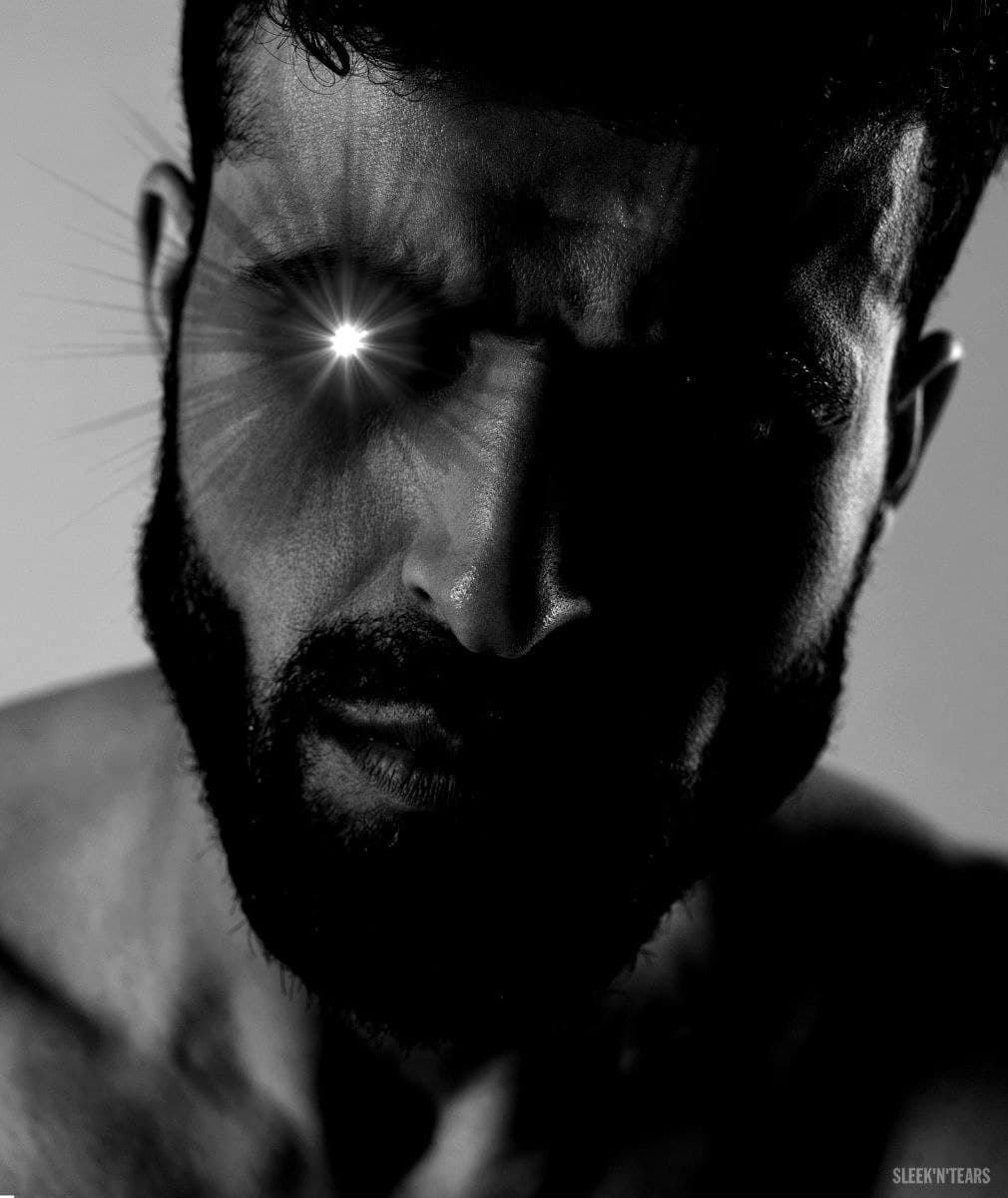 A strong man with a glowing eye in shadowy lighting.