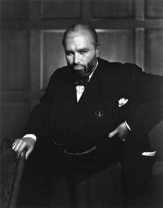 Man in formal attire standing confidently with a serious expression.