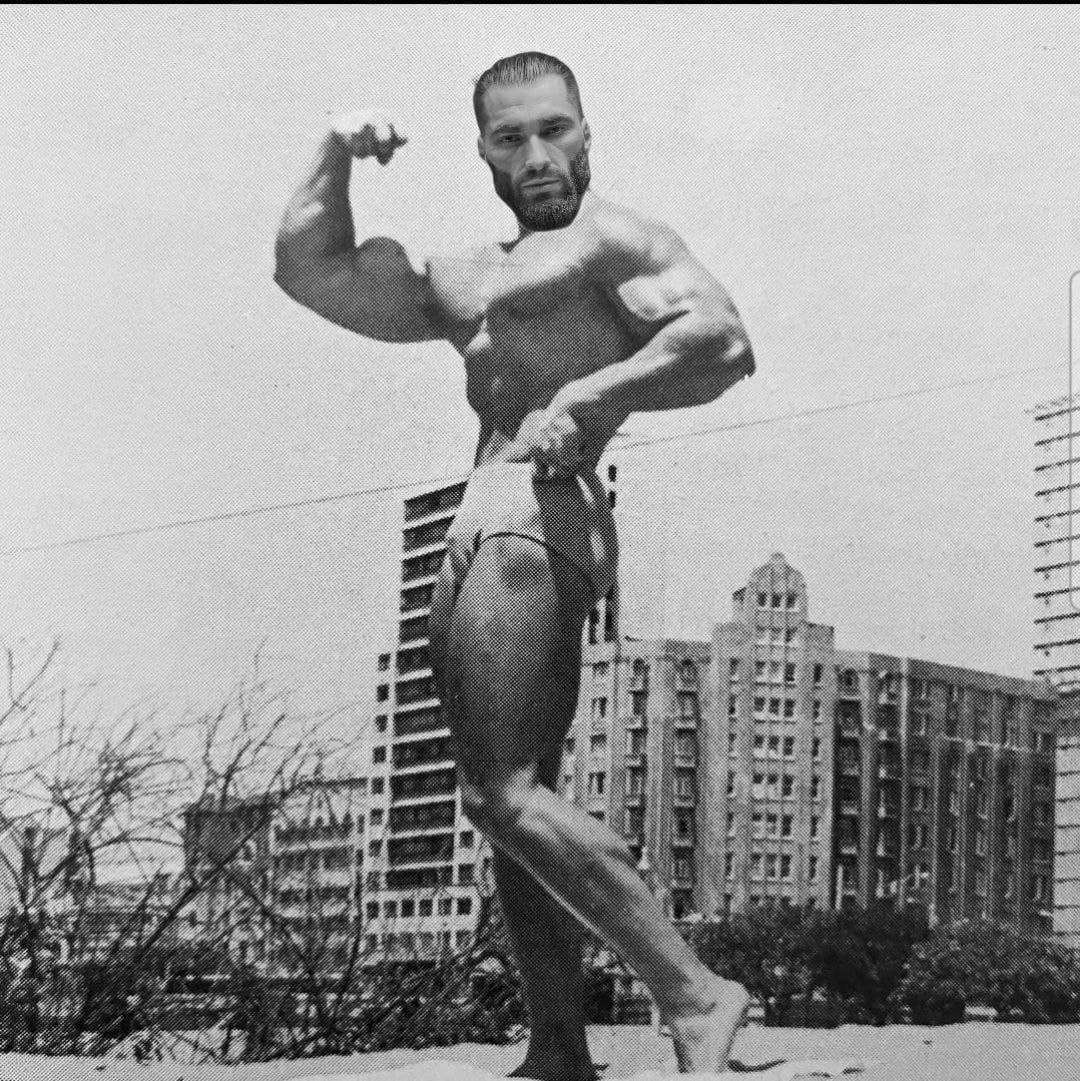 Muscular bodybuilder posing in a vintage urban setting.