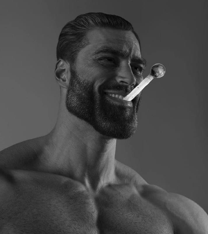 Muscular man with beard holding a joint in his mouth.