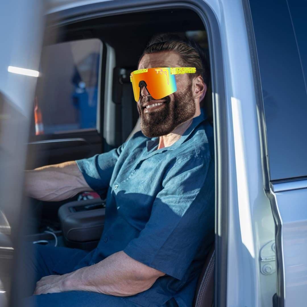 Muscular man in sunglasses sits confidently in a truck.
