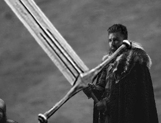 A confident figure with a large sword overseeing a kneeling character.