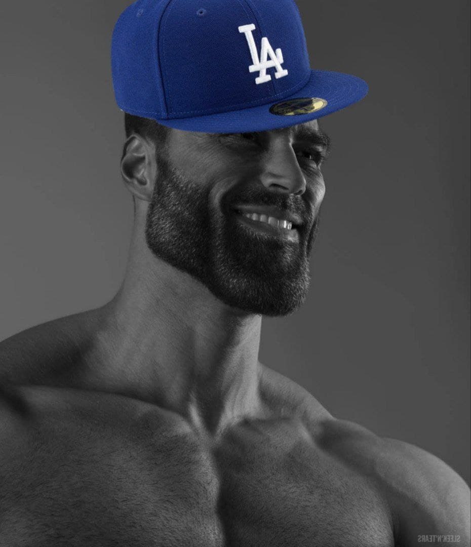 Muscular man wearing LA cap and smiling in grayscale.