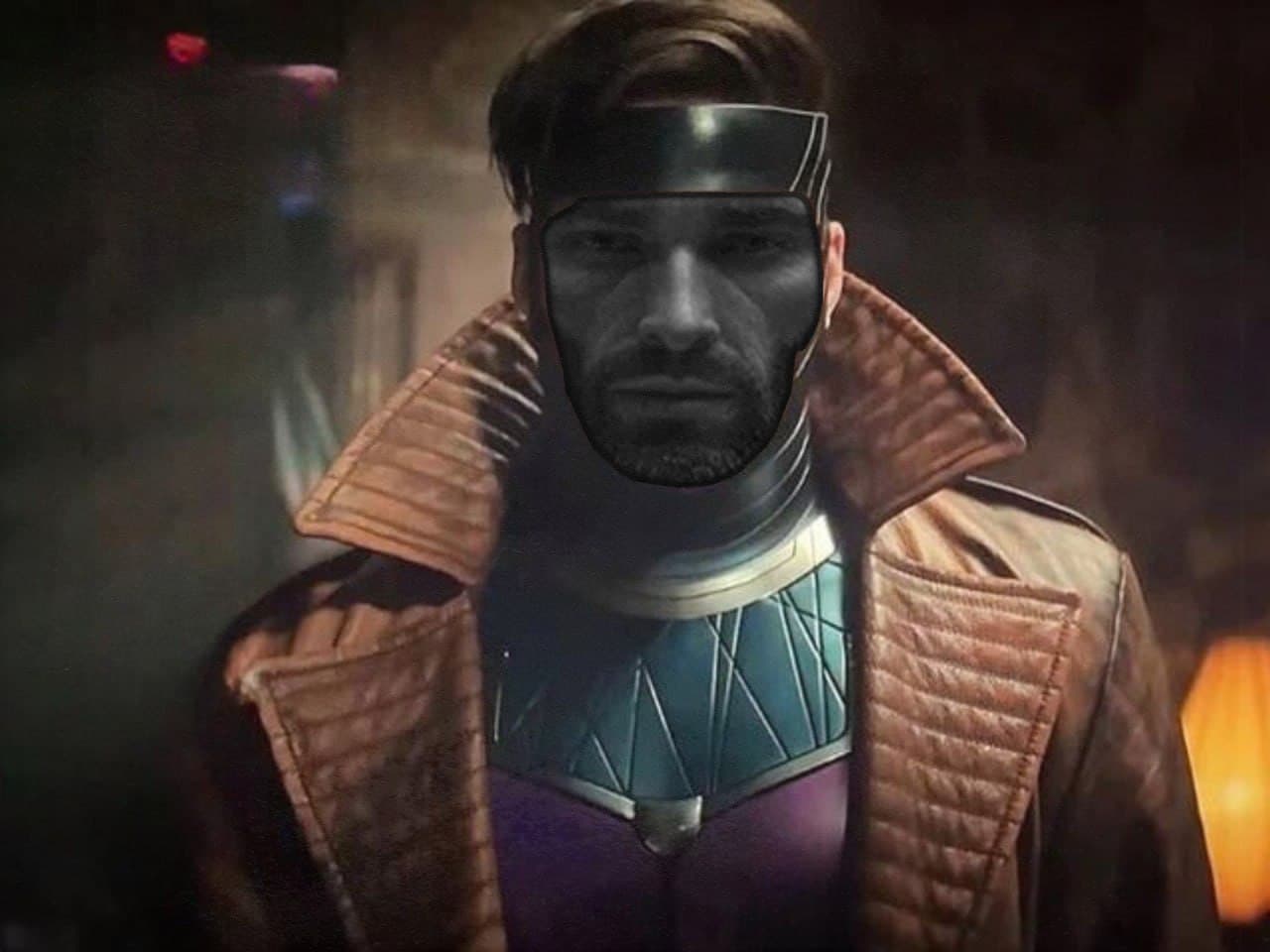Man in a superhero costume with a serious expression in dim lighting.