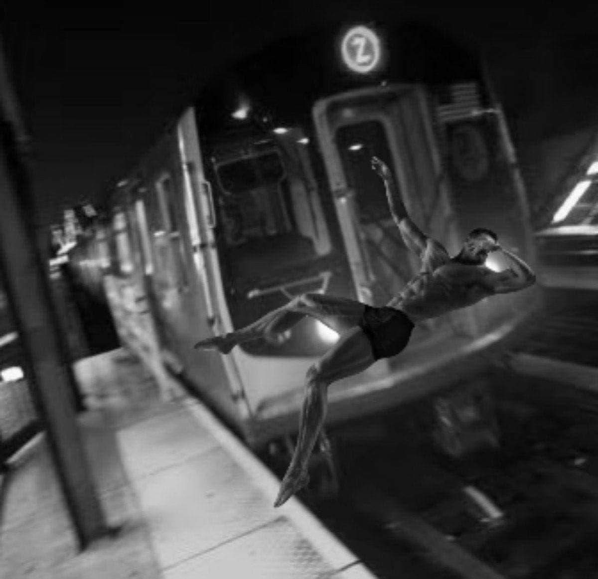 Muscular man posing near a subway train at night.