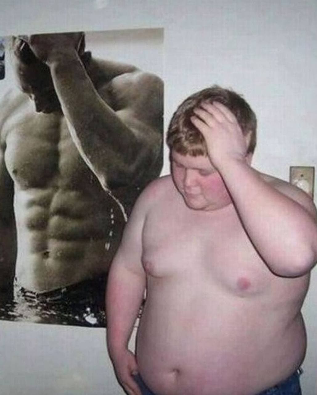 Young man looks disappointed next to muscular poster.