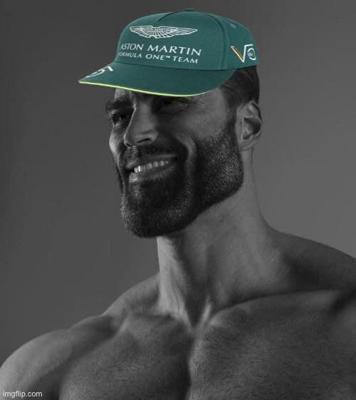 Muscular man smiling in an Aston Martin cap.