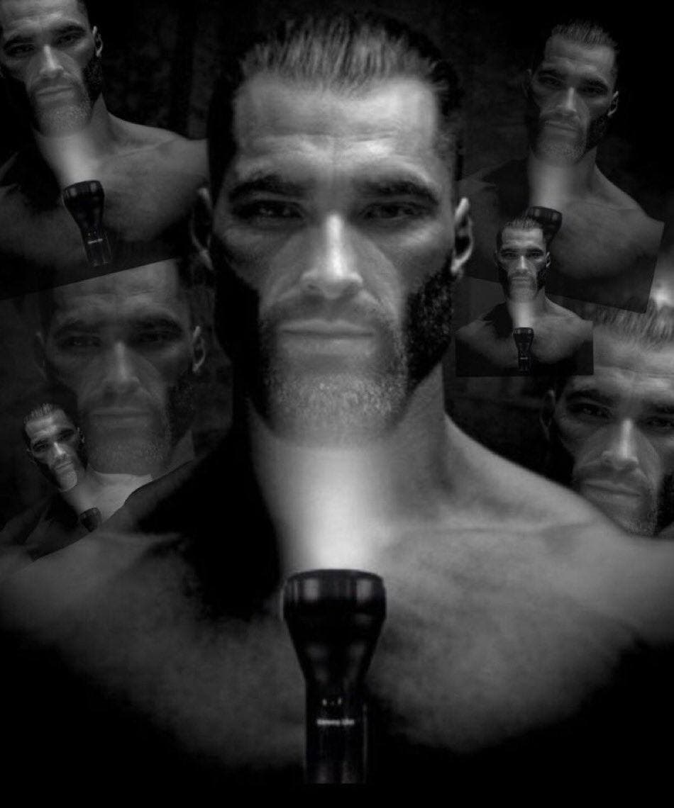 A muscular man illuminated by a flashlight in black and white.