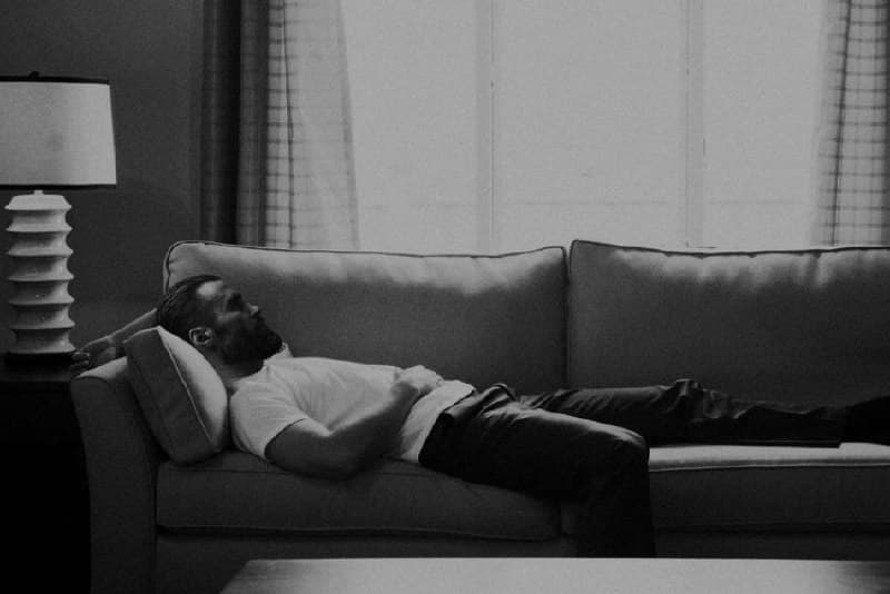 Man resting on a couch, deep in thought.