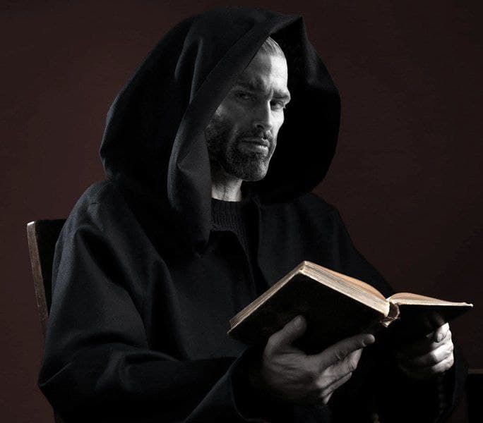 Mysterious figure reading a book in a dark hood.