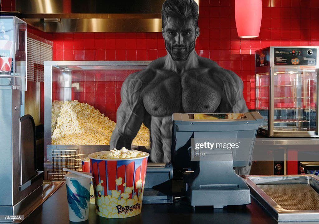 Muscular man at a concession stand with popcorn.