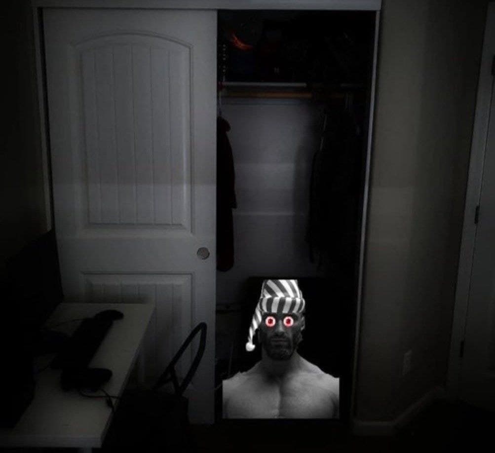 A muscular man with a striped hat in a dark closet.