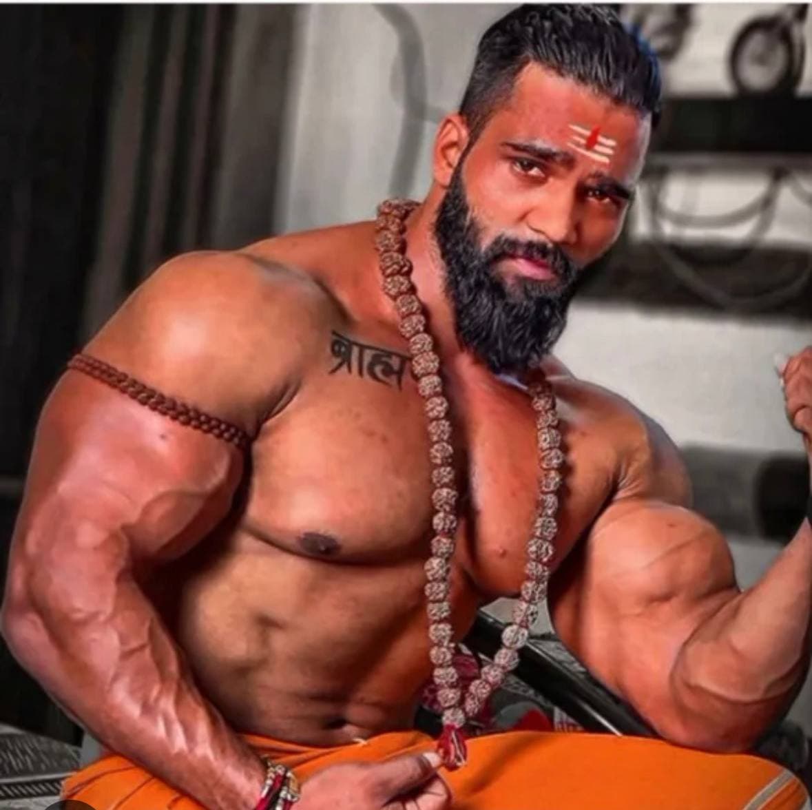 Muscular man in orange garment striking a pose.