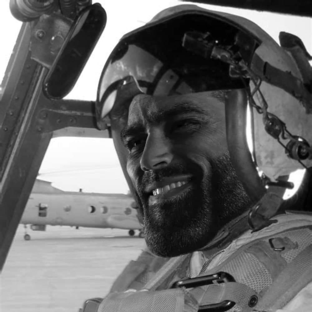 Pilot with a confident smile in helicopter cockpit.