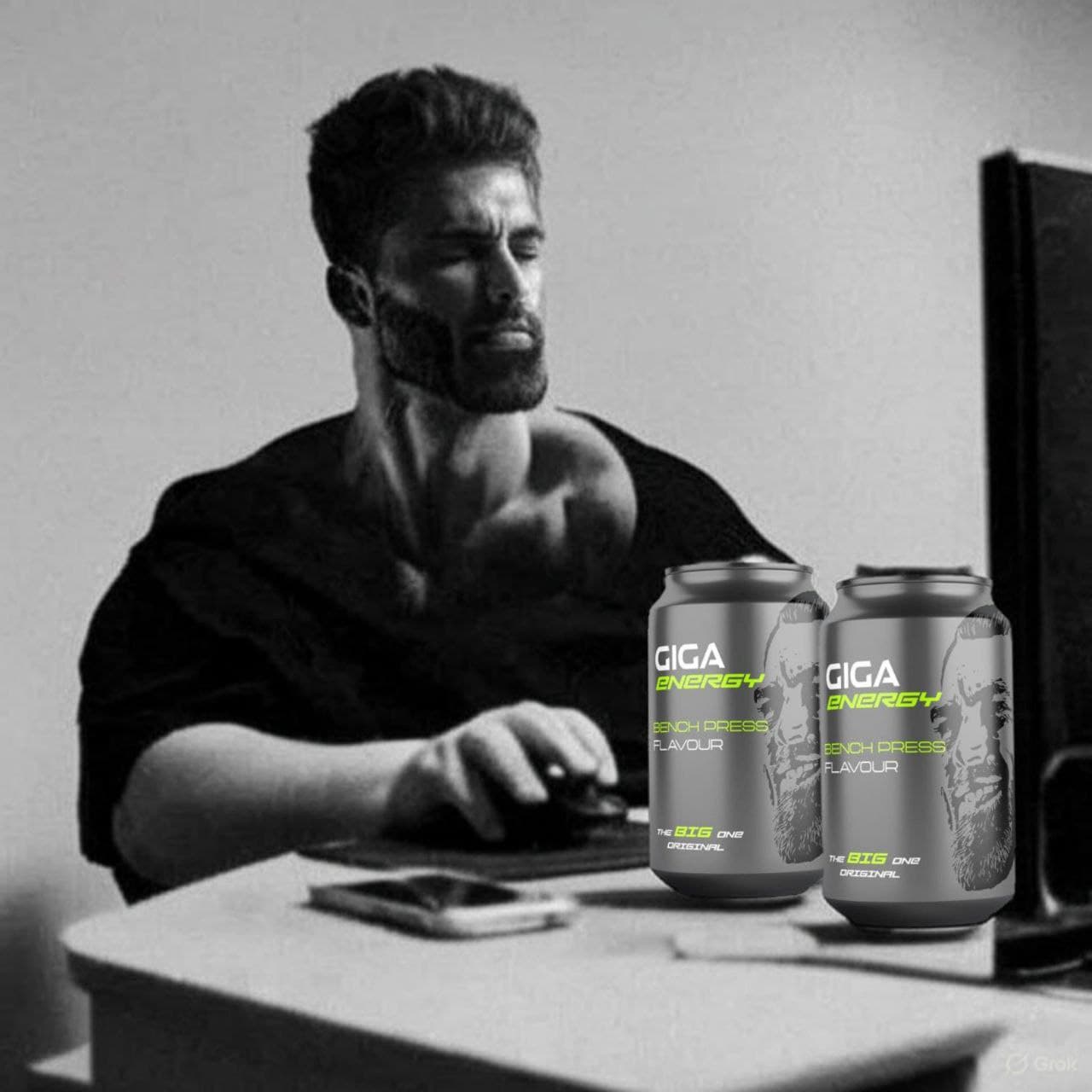 Muscular man focused on computer with Giga Energy drinks.