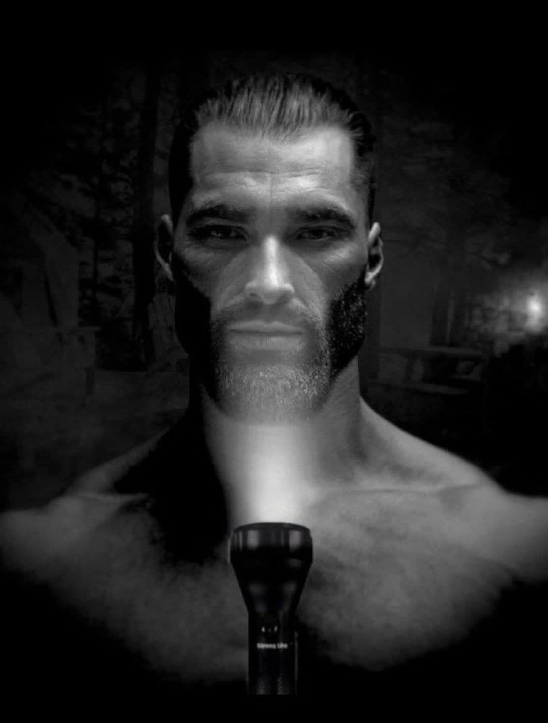 Muscular man with a flashlight in a dark setting.