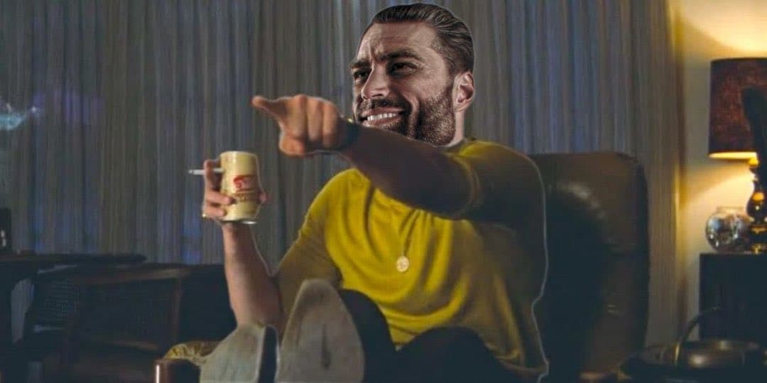 Man in yellow shirt pointing confidently while holding a drink.