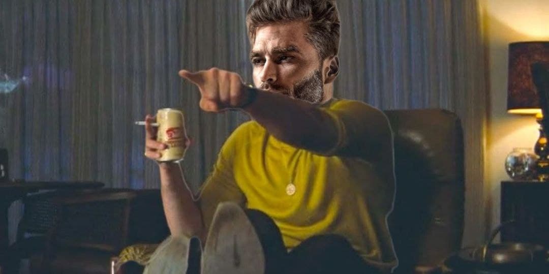 Muscular man points confidently, holding a beer in a cozy setting.