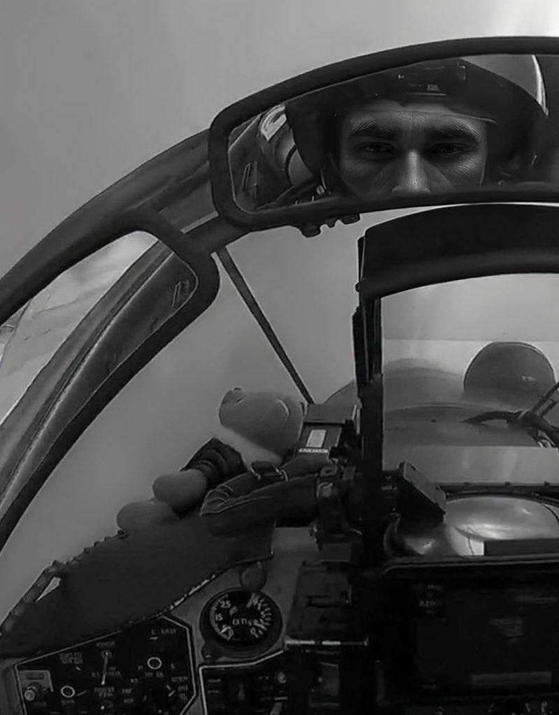 Pilot looking serious with a toy in the cockpit.