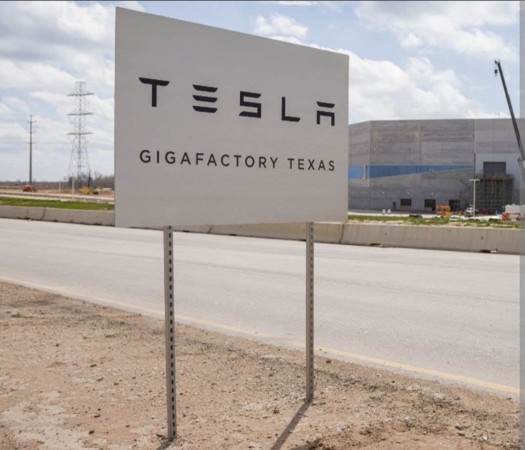 Tesla GigaFactory sign in Texas under a cloudy sky.