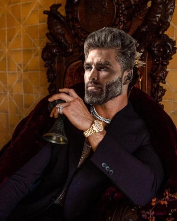 A confident man in luxurious attire holding a bell.