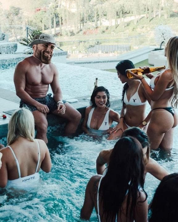 Confident man with women in swimwear at a pool.