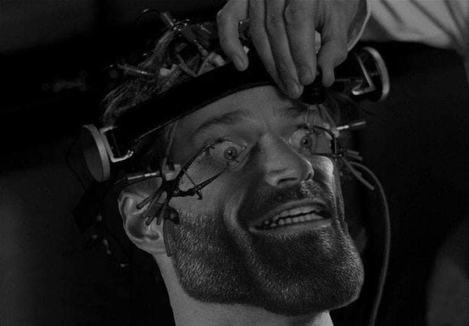 A smiling man with a beard in a strange experiment setup.