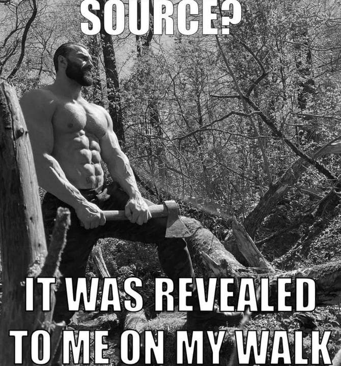 Muscular man holding an axe in a forest, looking contemplative.