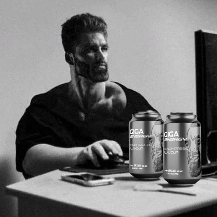 Muscular man concentrating on computer with energy drinks.