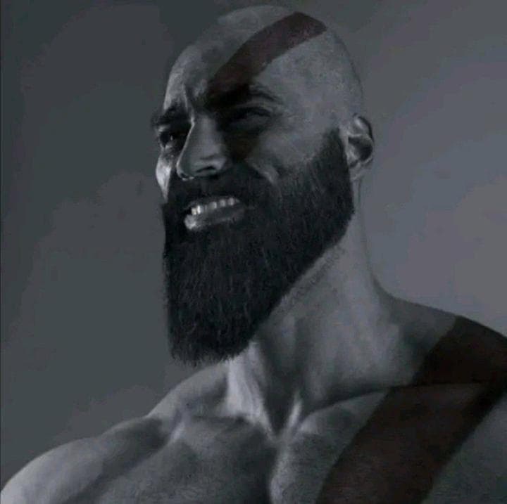 A muscular man with a beard smiling confidently.