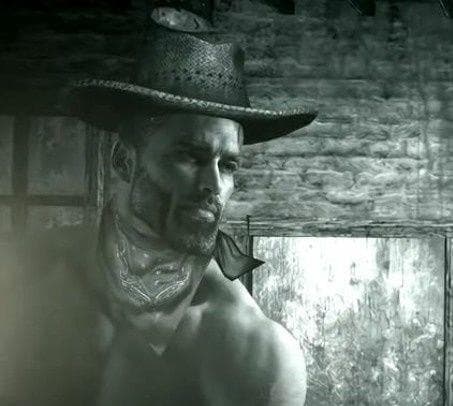 Muscular man with cowboy hat and bandana looking confidently.
