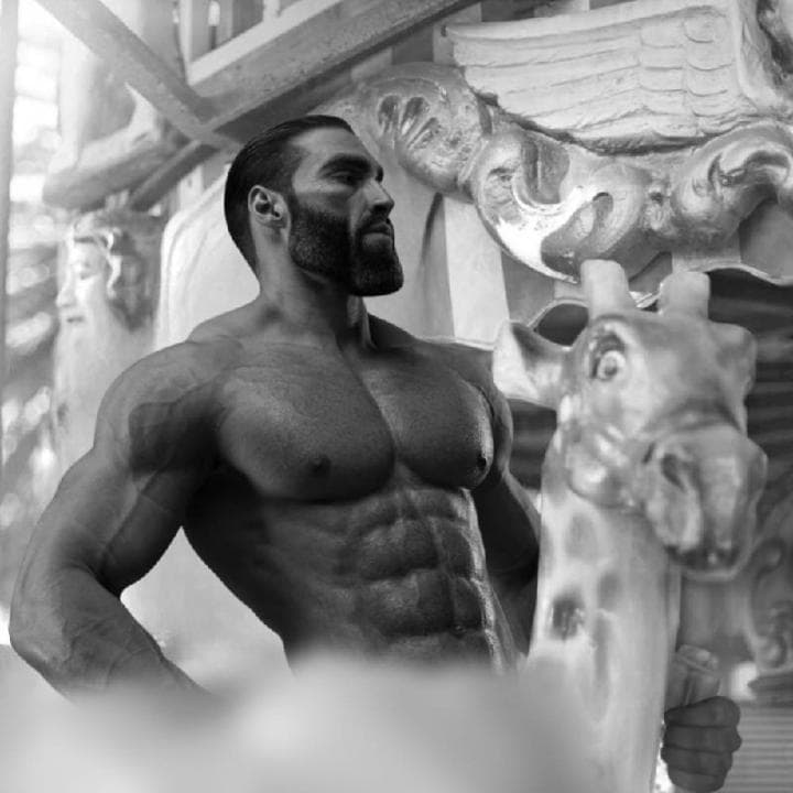 Muscular man posing next to a giraffe statue.