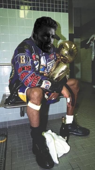 Athletic man celebrating with a trophy in a locker room.