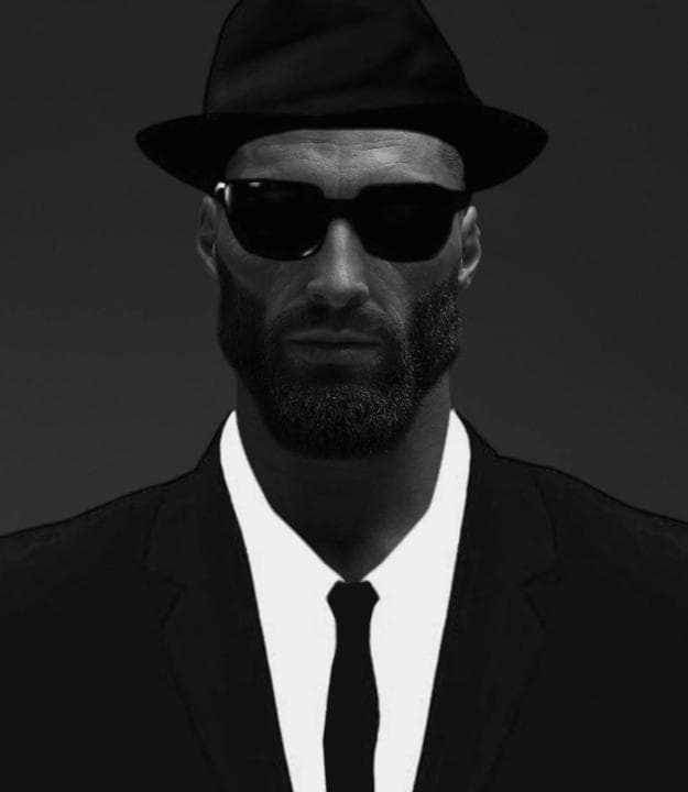 Muscular man in a suit with sunglasses and a fedora.