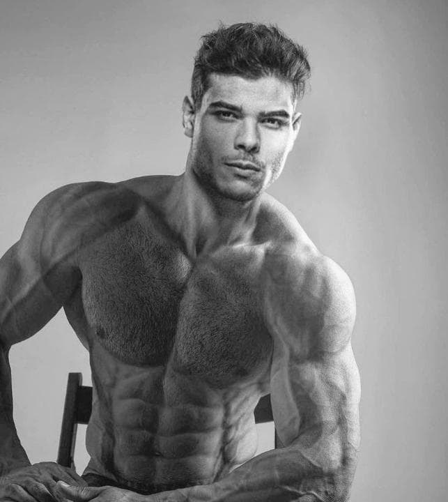 Muscular man sitting confidently on a chair.