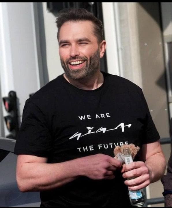 Confident man in GigaChad shirt holding a drink and snack.