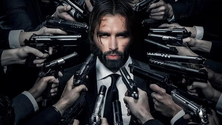 Man in suit surrounded by hands holding guns.